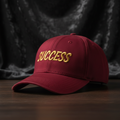 Success embroidered baseball cap in burgundy with gold embroidery
